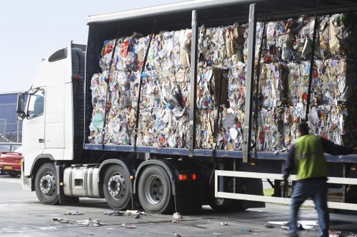 Worker wearing PPE handling waste container